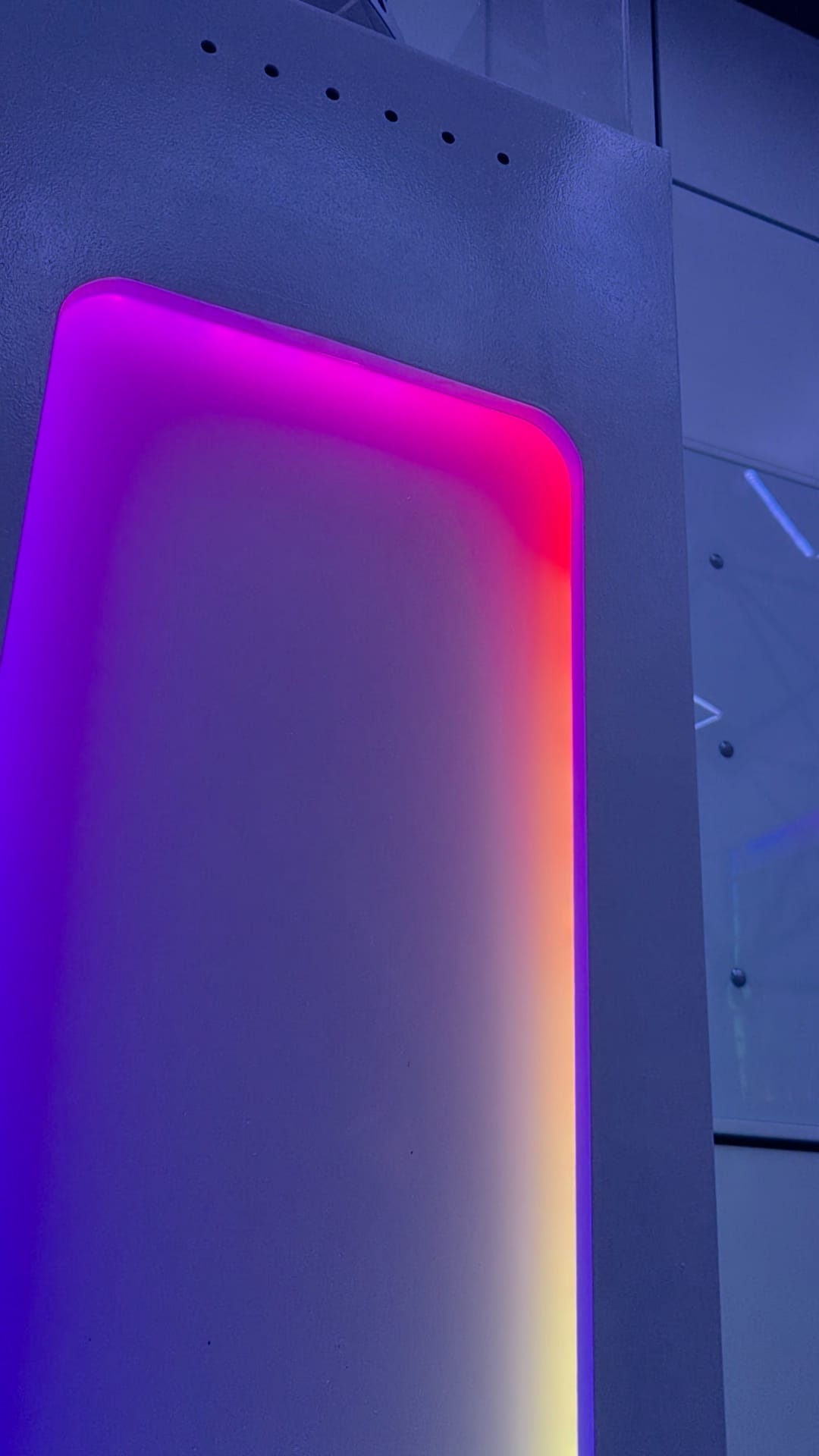 Paars en rood oplichtend paneel in een witte wand